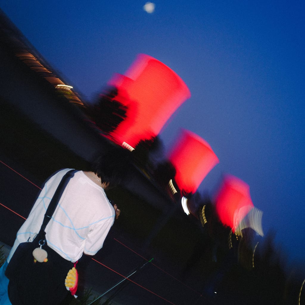 夜色里站在红灯笼下的人，深蓝色天空，天上有一轮月亮